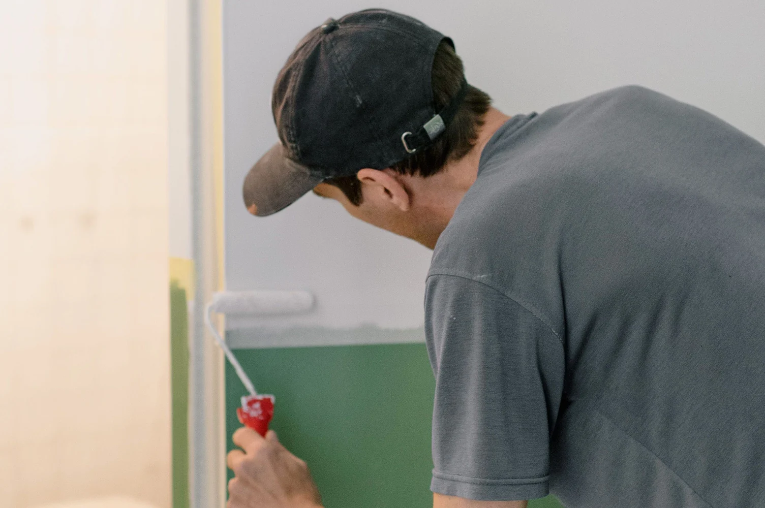 Peintre décorateur à Caen appliquant une peinture vert sauge au rouleau sur un mur intérieur